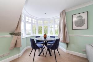 a dining room with a round table and blue chairs at The Lewisham Flats in London