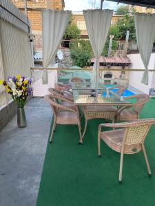 a patio with a glass table and chairs and flowers at TownHouse with pool in Yerevan