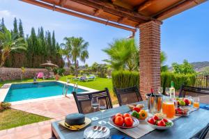 una mesa con comida junto a una piscina en Villa Paraiso Dos by Villa Plus, en Frigiliana
