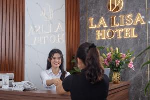 a woman sitting at a reception desk in a hotel at La Lisa Hotel in Hanoi