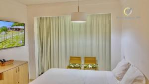 1 dormitorio con 1 cama blanca y 2 sillas en Flat beira-mar vista mar, en Natal