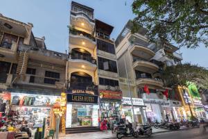 a building with shops on the side of a street at La Lisa Hotel in Hanoi