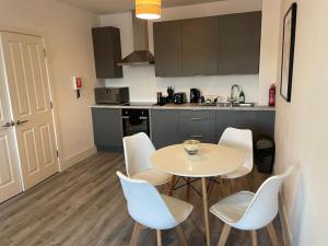 a kitchen with a table and white chairs in a room at Beautiful Flat In Woking Central in Woking
