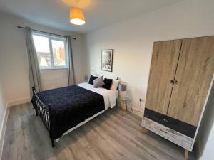 a bedroom with a bed and a large wooden cabinet at Beautiful Flat In Woking Central in Woking