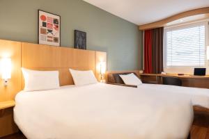 ein großes weißes Bett in einem Hotelzimmer in der Unterkunft ibis Genève Centre Nations in Genf