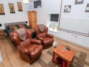 a living room with two leather chairs and a table at Barn 3 in Swansea