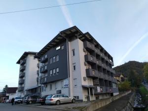 a building with cars parked in a parking lot at Apartman Harmony 2 in Banja Koviljača