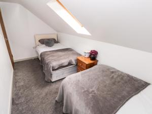 een slaapkamer op zolder met 2 bedden en een nachtkastje bij Barn 2 in Swansea
