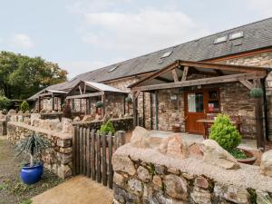 a stone house with a stone wall and a fence at Barn 2 in Swansea