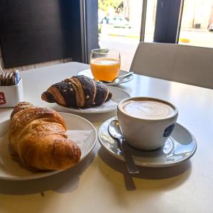 una mesa con dos platos de cruasanes y una taza de café en B&B Palazzo 1906 - Eco dimora storica, en Bitetto