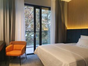 um quarto com uma cama, uma cadeira e uma janela em Avenue21 em Zagreb