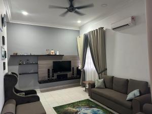 a living room with a couch and a television at Homestay Triang in Kampong Kerayong