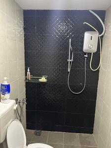 a bathroom with a shower with a black tile wall at Homestay Triang in Kampong Kerayong