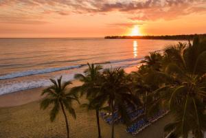 喀巴里特Viva Tangerine by Wyndham, A Trademark All Inclusive的日落时分拥有棕榈树和海洋的海滩
