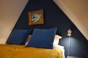 een slaapkamer met blauwe muren en een bed met blauwe kussens bij Stijlvol appartement 'Moto' in centrum Franeker. in Franeker