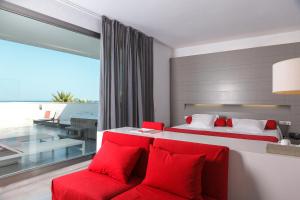 a bedroom with two beds with red pillows at Hotel Spa Calagrande Cabo de Gata in Las Negras