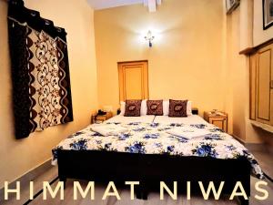 a bedroom with a bed with a blue and white comforter at Hotel Himmat Niwas in Jaisalmer
