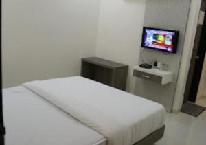 um quarto com uma cama branca e uma televisão em Hotel Lotus Chandrapur em Chandrapur
