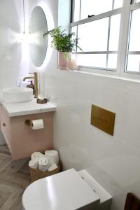 W białej łazience znajduje się umywalka i lustro. w obiekcie Sandpiper Studio w mieście Scarborough