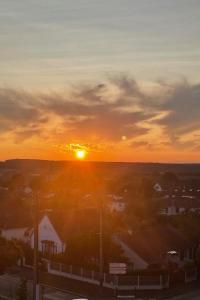 a sunset over a small town with the sun setting at Appartement Cosy Beauvais in Beauvais