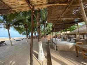 Ouoran的住宿－Keur des pecheurs chez ivan，海滩上带吊床的度假村