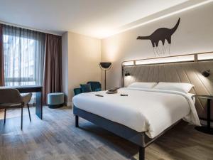 ビーレフェルトにあるibis Styles Bielefeld Cityの大きなベッドとデスクが備わるホテルルームです。