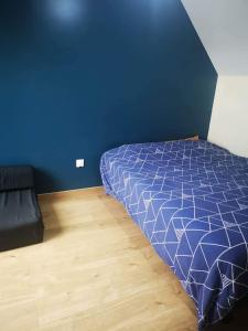 um quarto azul com uma cama e piso em madeira em Le Mans Fay sa course em Fay
