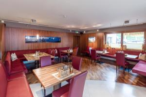 a restaurant with wooden walls and tables and red chairs at Hotel Sonnleiten in Bruck am Ziller