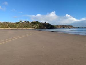 a sandy beach with houses on a hill next to the water at Tenby house for 6 with 2 parking spaces in Pembrokeshire
