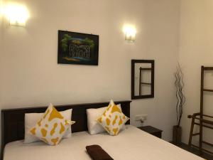 a bedroom with a bed with yellow and white pillows at Villa D40 in Weligama