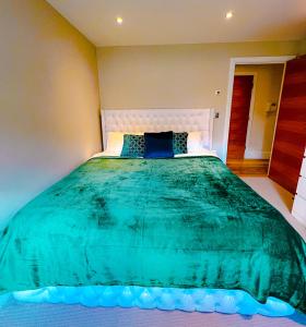 a bedroom with a large bed with a green comforter at My Richmond London SUPER KING Size Bed in Kew