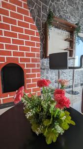 un jarrón de flores en una mesa frente a una chimenea de ladrillo en kollanoor guest house en Madikeri