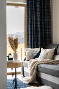 Una sala de estar con un sofá y una ventana. en Domek Zakopane Tatrzański Kącik APARTZAKOP, en Zakopane