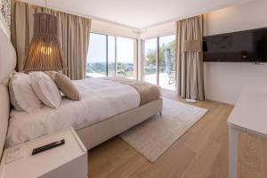 una camera da letto con un letto, una TV e porte scorrevoli in vetro di Villa Paulina MOUGINS a Mougins Altre 37 foto