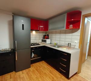 a kitchen with red cabinets and a stainless steel refrigerator at Central Park Apartments in Braşov