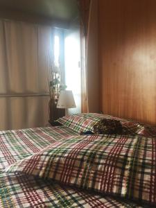 een slaapkamer met een bed met een geruite deken en een raam bij ABITARE MARILLEVA in Trento