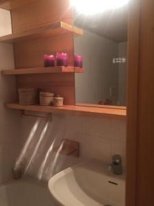 een badkamer met een wastafel, een spiegel en roze kaarsen bij ABITARE MARILLEVA in Trento