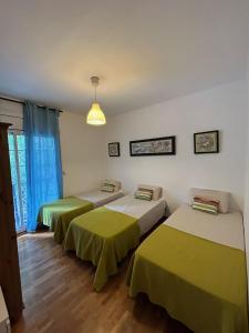 a room with three beds with green sheets at GranVia Fira Apartment in Hospitalet de Llobregat