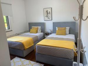 um quarto com 2 camas com lençóis amarelos e cinzentos em Casa 212 em Ponta do Sol