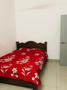 a bed with a red blanket with flowers on it at D' HOME MERIDIAN in Kluang