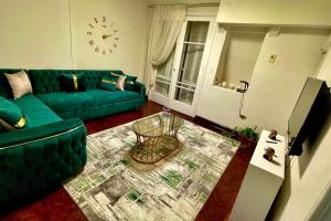 a living room with a green couch and a clock at Formidable of Cairo in Cairo