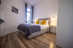 a bedroom with a bed with yellow pillows on it at InPoint Cracow Apartments - Near Main Market Square in Krakow