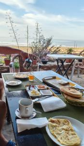 a table with plates of food and a cup of coffee at SurfcampLagrotte in Essaouira