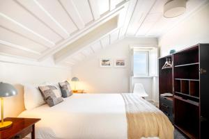 a bedroom with a large white bed and a ceiling at Chiado Trindade Apartments | Lisbon Best Apartments in Lisbon
