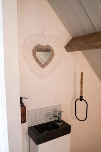 ein Badezimmer mit einem Waschbecken und einem herzförmigen Spiegel in der Unterkunft Ma Maison d'Autre 