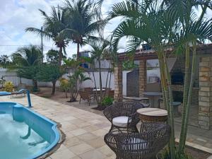 einen Pool mit Stühlen, einem Tisch und Palmen in der Unterkunft POUSADA PARAISO DO GAUCHO in Córrego das Panelas