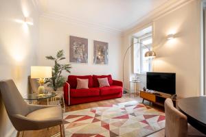 a living room with a red couch and a tv at Chiado Trindade Apartments | Lisbon Best Apartments in Lisbon