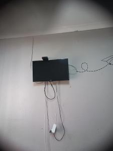 a television hanging on a wall with a wire at Prime Guest Inn in Benoni
