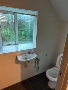 baño con aseo y lavabo y ventana en Bahagia Makmur Homestay, en Temerloh