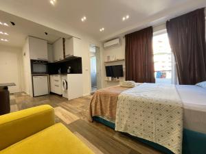 um quarto de hotel com uma cama e um sofá amarelo em Boutique Central Studio Apartments em Tirana